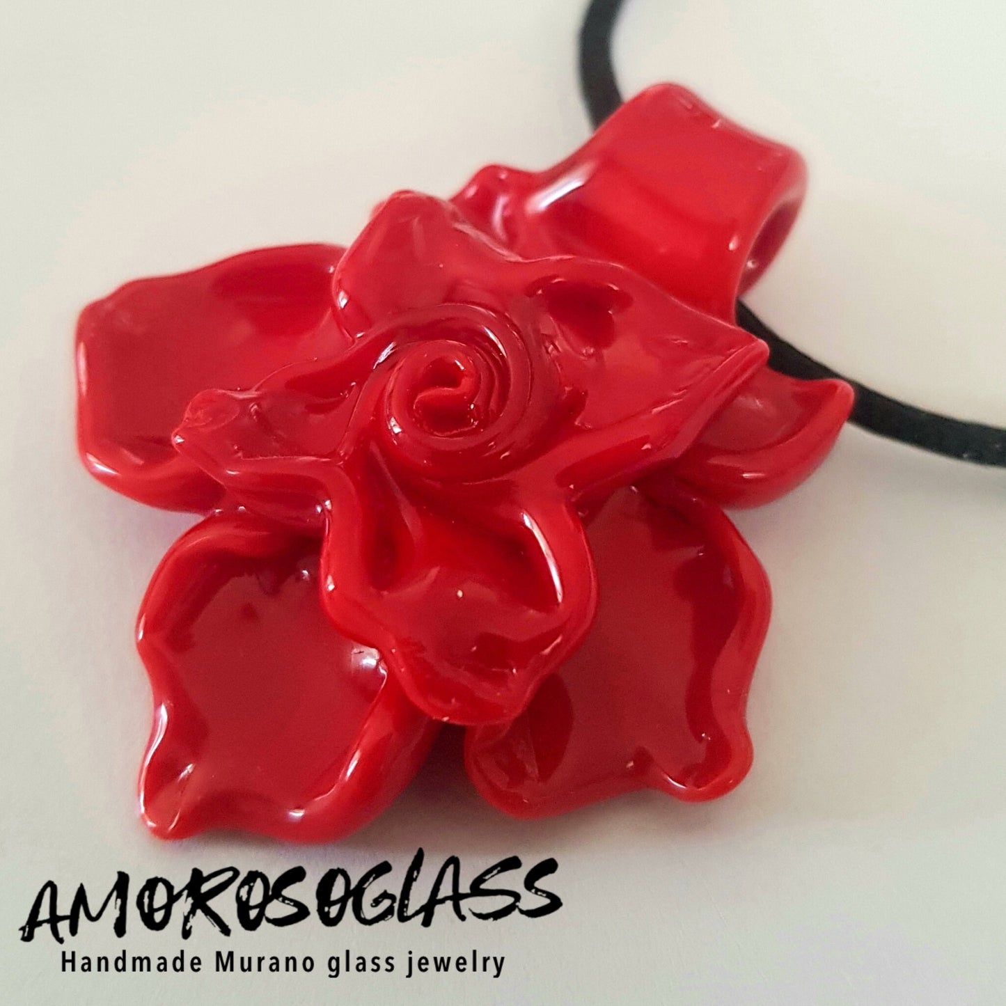 Fiore in vetro di murano colore rosso pieno. Un petalo è arricciato all'indietro a formare il gancio per far passare il collarino.